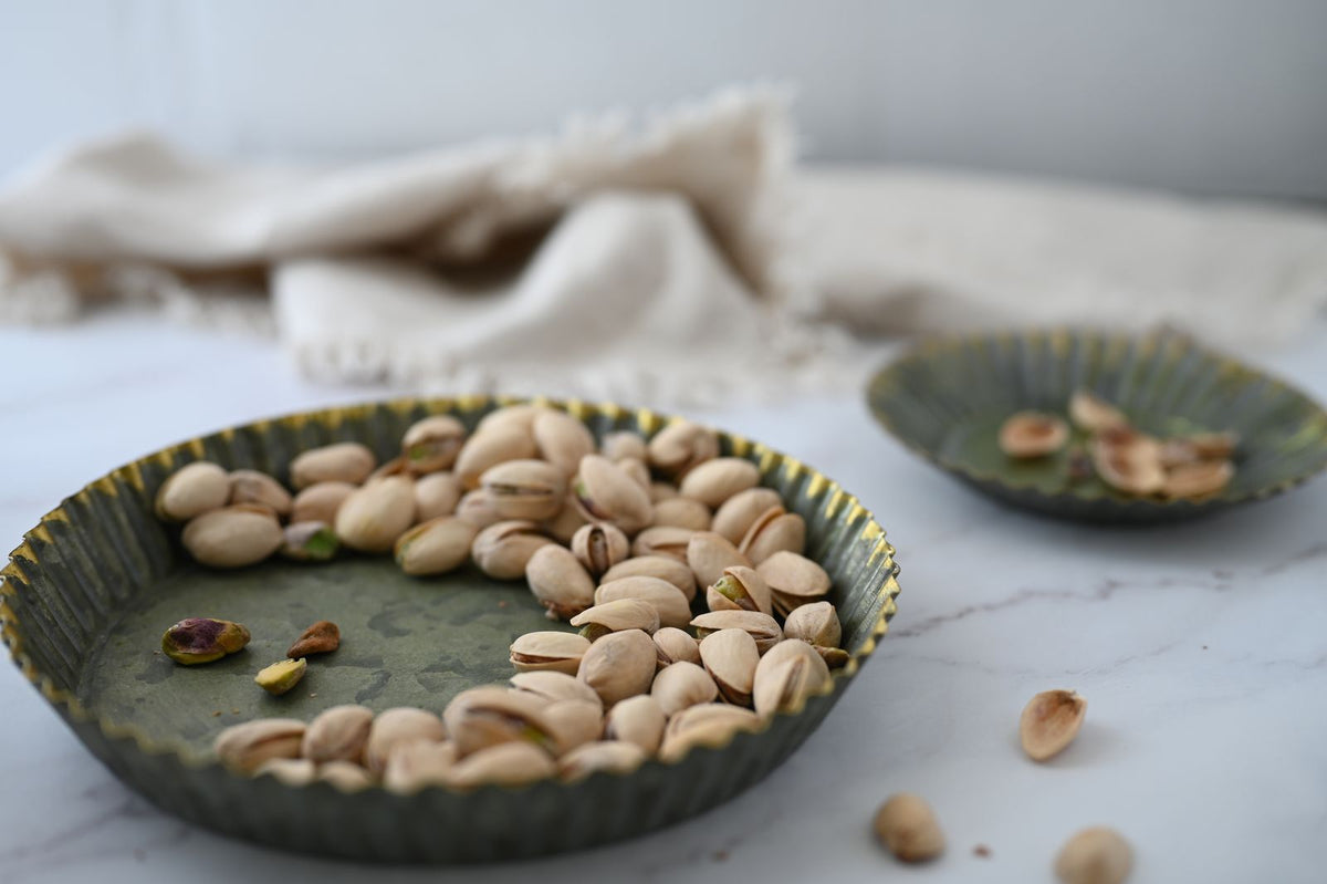 Pistachios in a rustic green bowl on marble